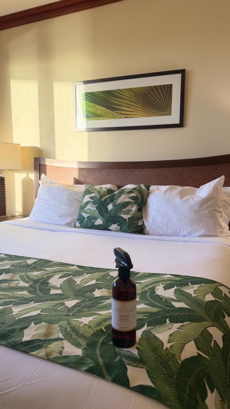 Final touch: linen spray on a made bed with a tropical palm-leaf runner and matching pillows