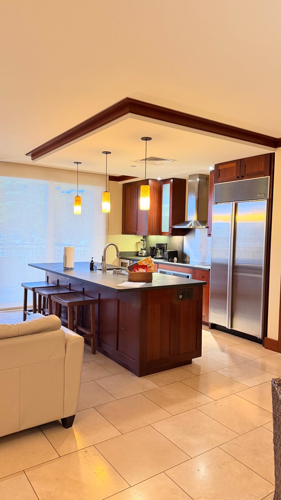 Clean, guest-ready kitchen with a wood island, stainless steel refrigerator and polished tile floor in an Oahu rental