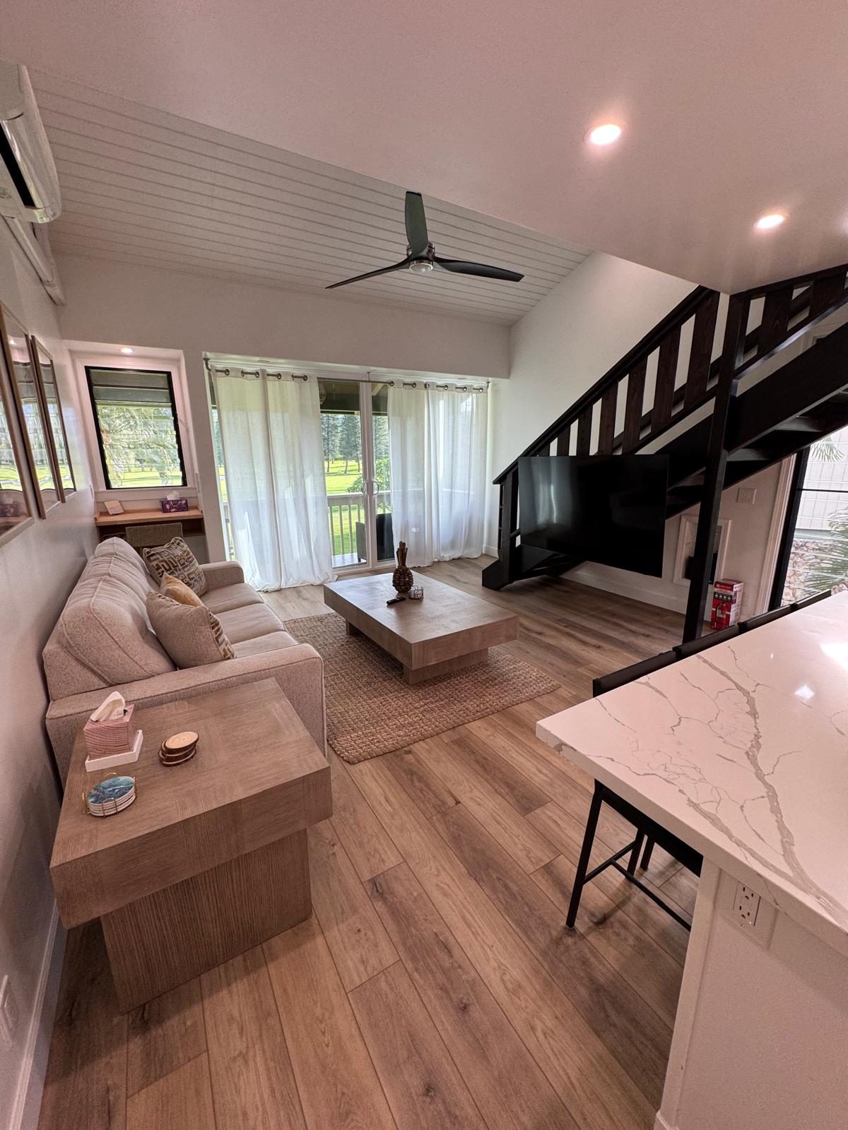 Tidy open-plan living room with a staged sofa, coffee table and vaulted ceiling in a North Shore vacation rental